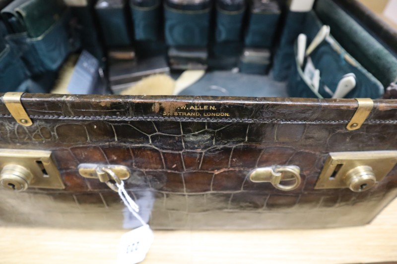 A crocodile skin travelling toilet case, containing silver topped glass jars,